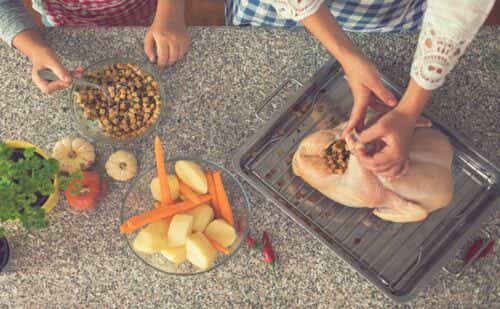adult and child stuffing a raw turkey on a counter