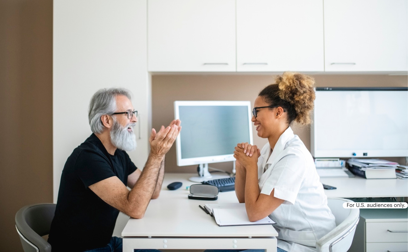 older man sits across desk facing doctor