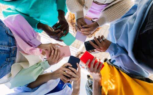 group of teens standing in a circle looking down at their phones