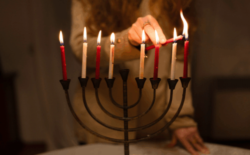 woman lighting a hanukkah menorah