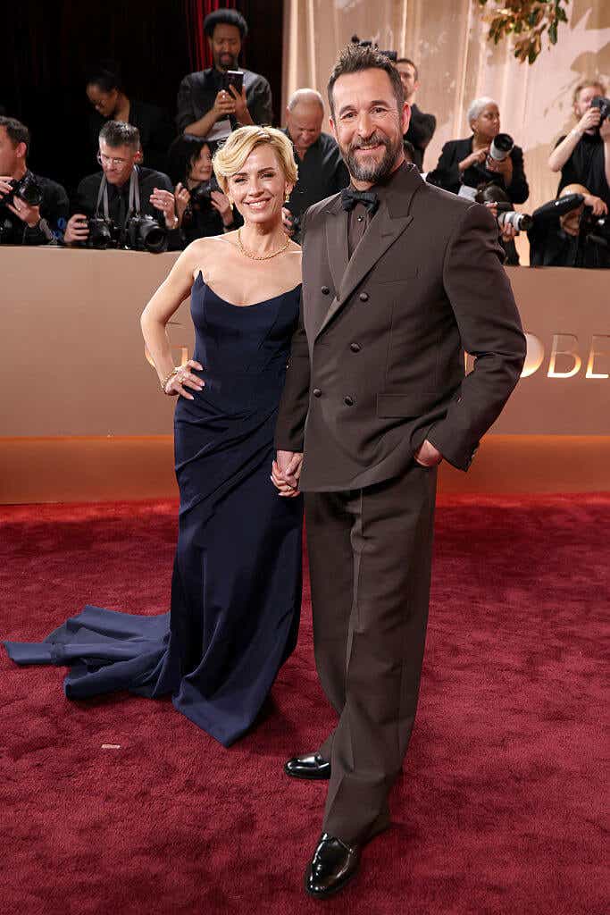 Sarah Wells wears a navy gown with a dramatic pointed neckline and Noah Wylie wears a brown tux.