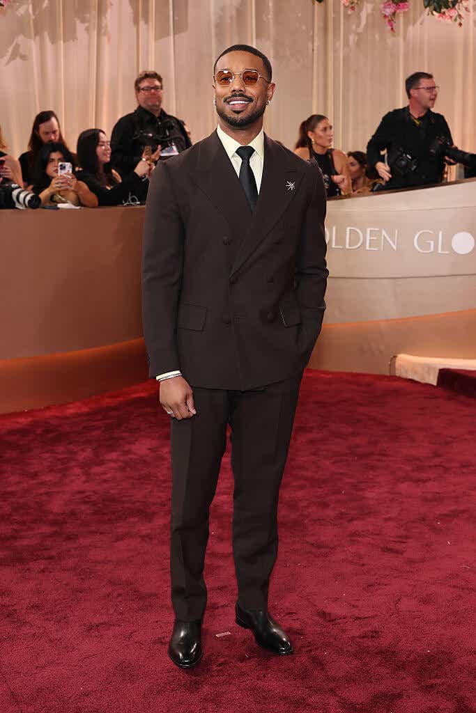 Michael B. Jordan wears a dark brown suit and brown sunglasses 