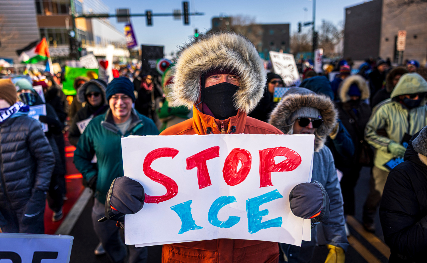Man holds a sign reading "STOP ICE"