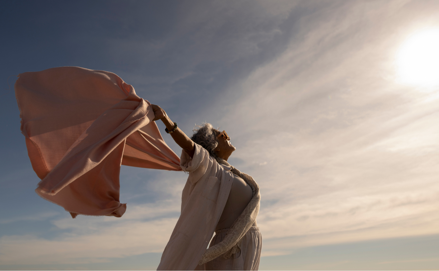 Carefree woman holding her shirt behind her as it billows in the breeze