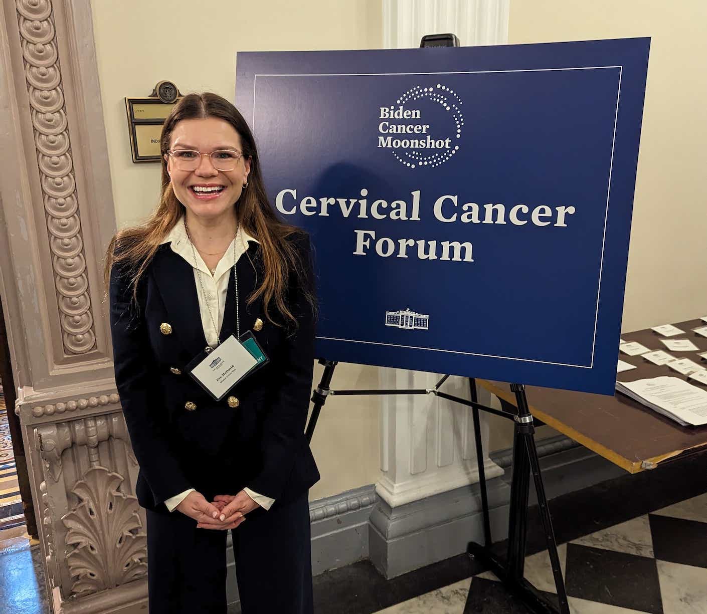 eve mcdavid standing in front of a sign that says "cervical cancer forum"