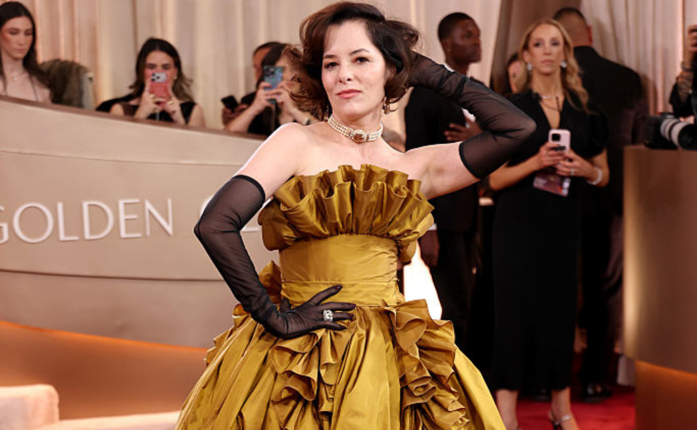 parker posey strikes a pose in her ruffled gold ballgown