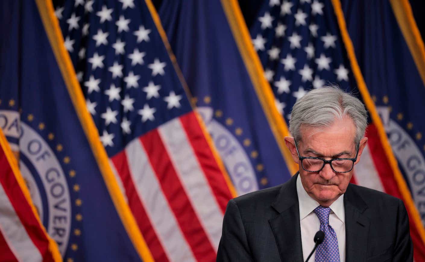 jerome powell looking down with american flags in the background