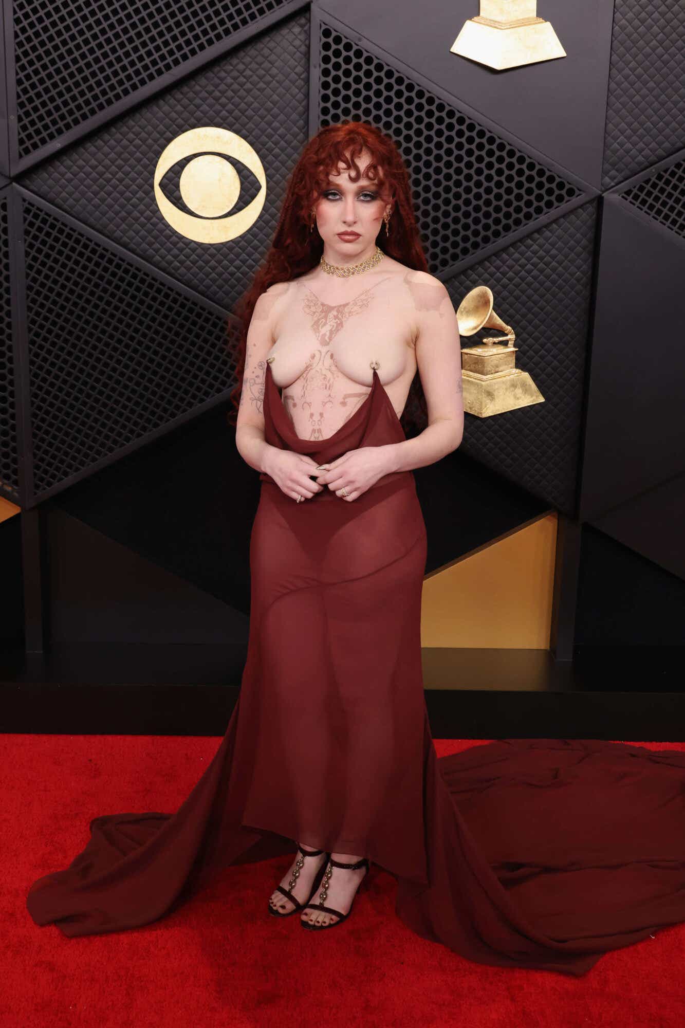 Chappell Roan wears a sheer dark red gown that is attached to her nipples via rings.