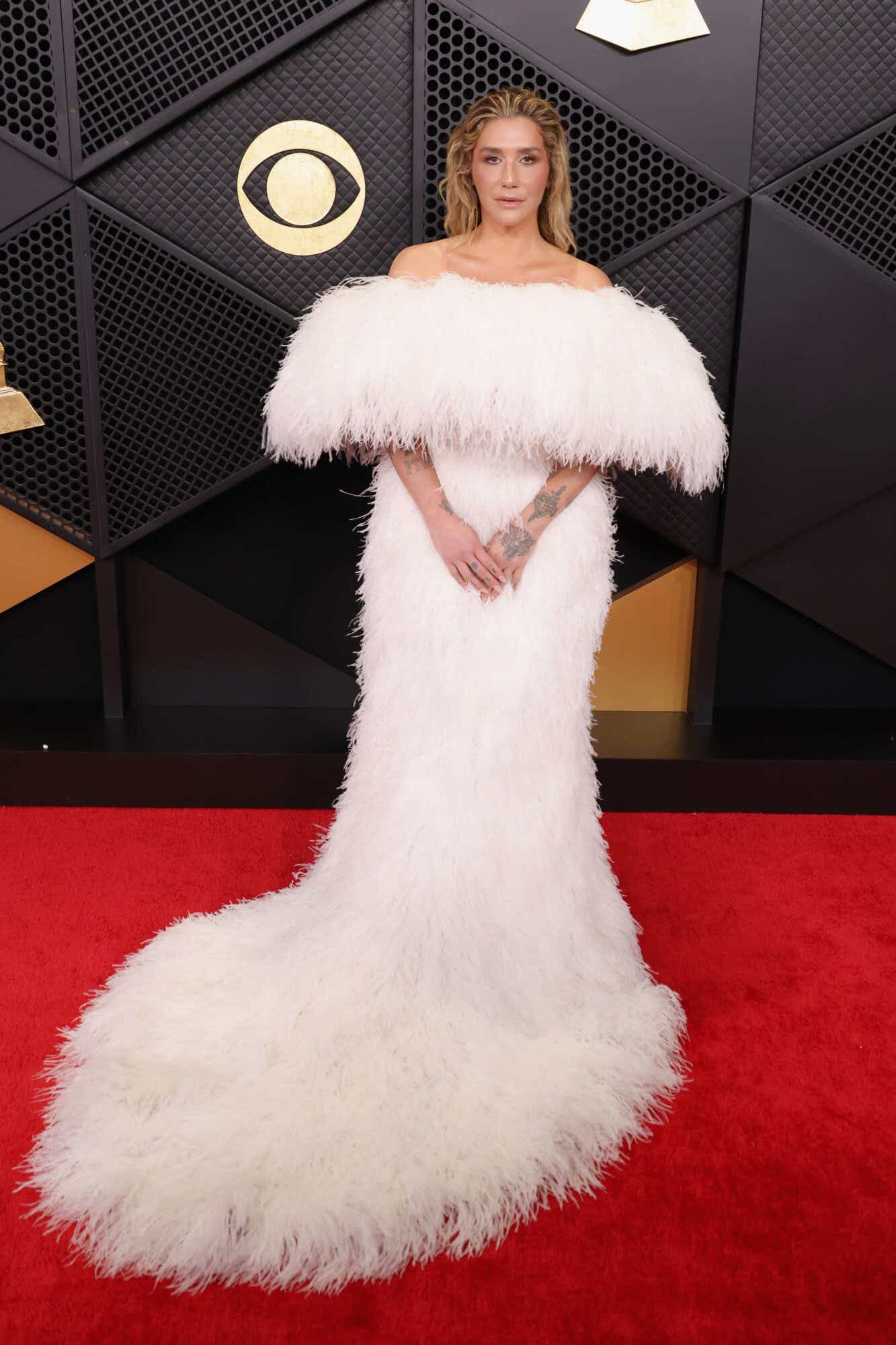 Kesha wears an all-white feathered gown with a big off-the-shoulder neckline