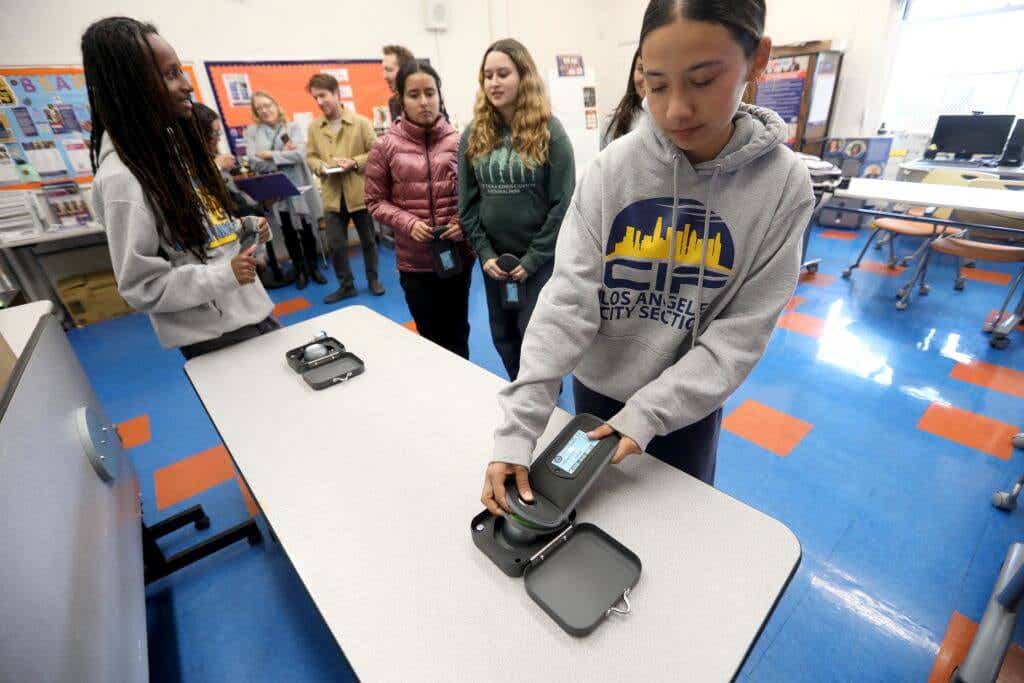 A high school senior shows how to unlock a magnetic pouch that holds her smartphone at University High School Charter in Los Angeles in March 2025.
