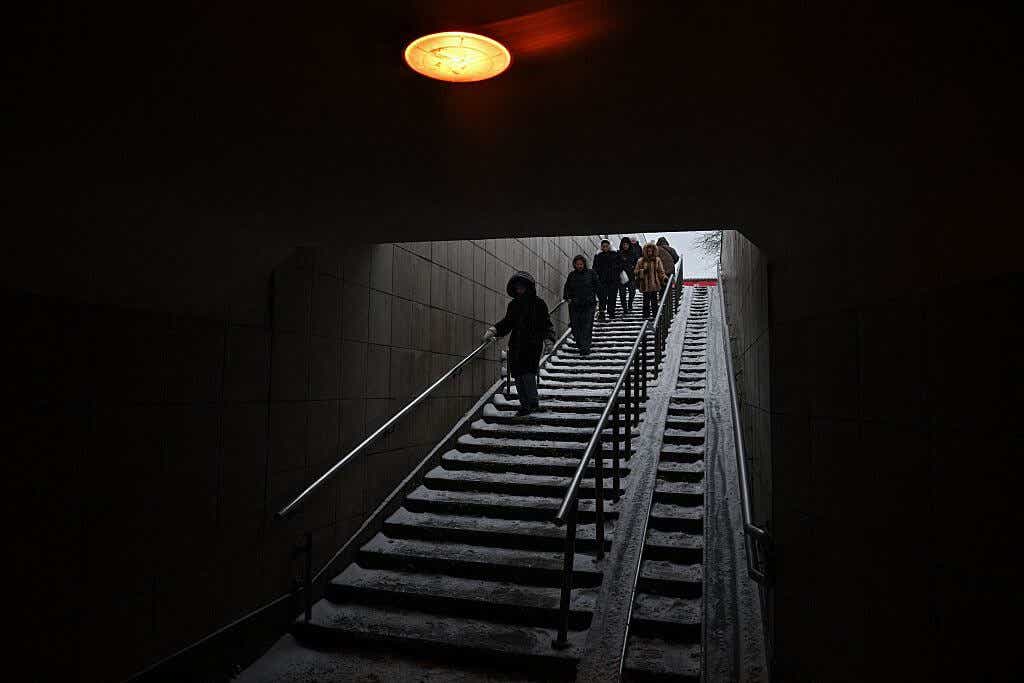 Russians descending the stairs into a dark Moscow subway station.