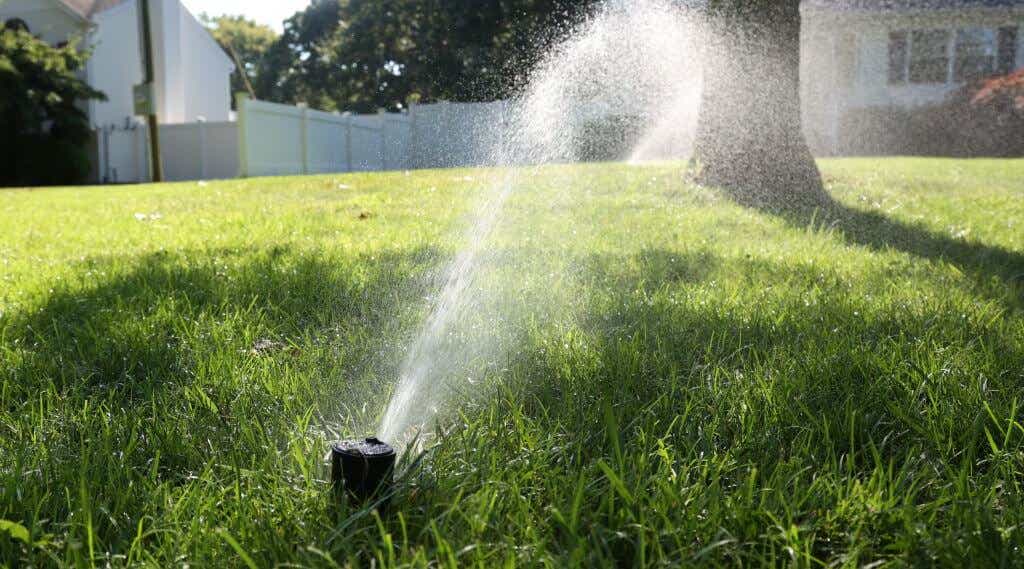 A lawn being watered by a sprinkler.