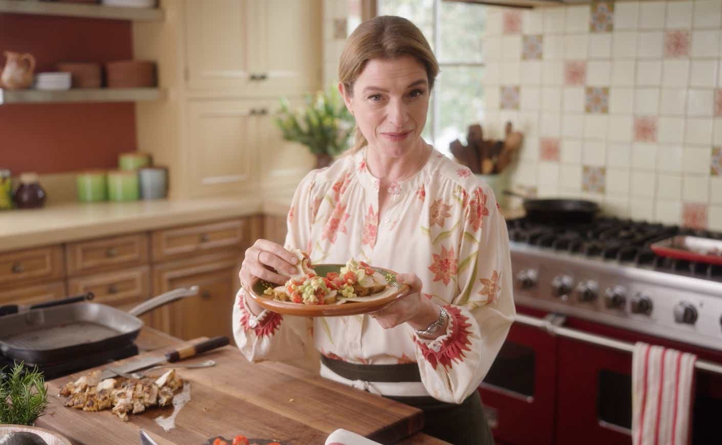 chef pati jinich in a kitchen holding a plate of tacos