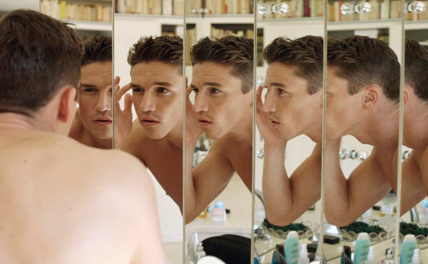 a man looking at his face in a mirror