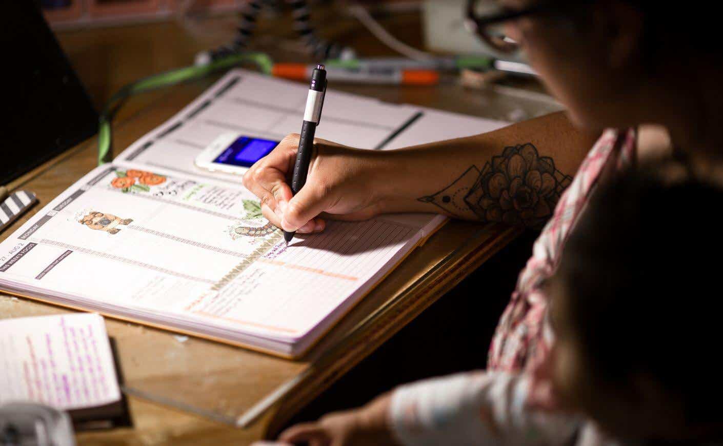 A person filling out a planner.