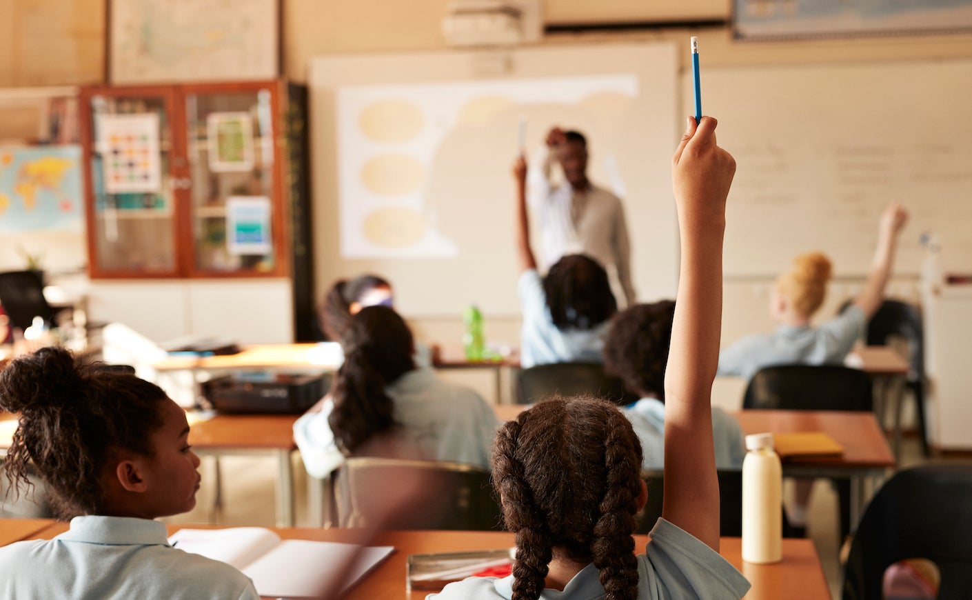 Girl raising hand and answering in classroom