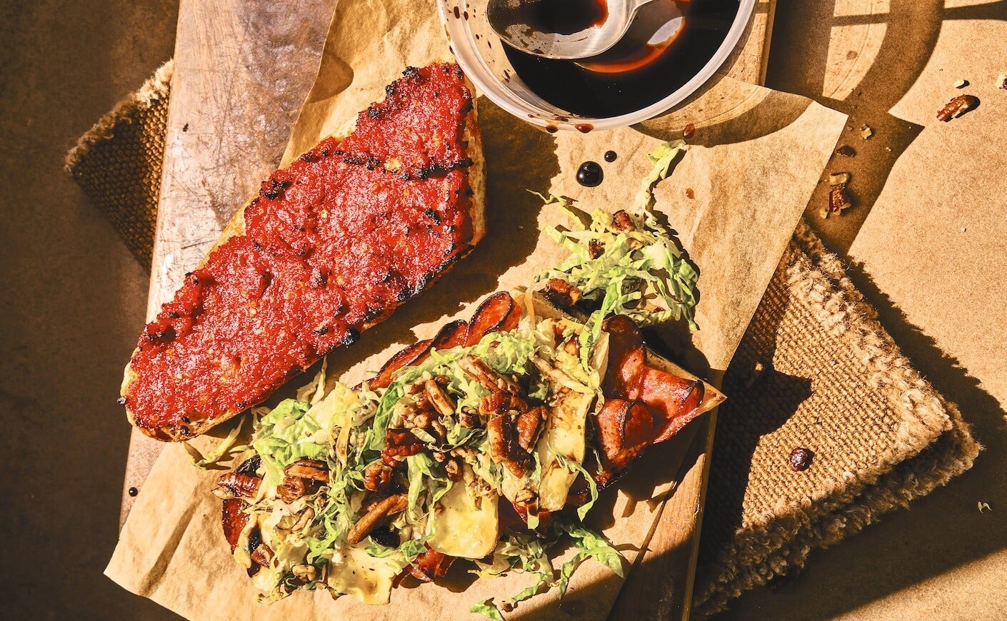 An open faced salami, brie, and sundried tomato spread sandwich.