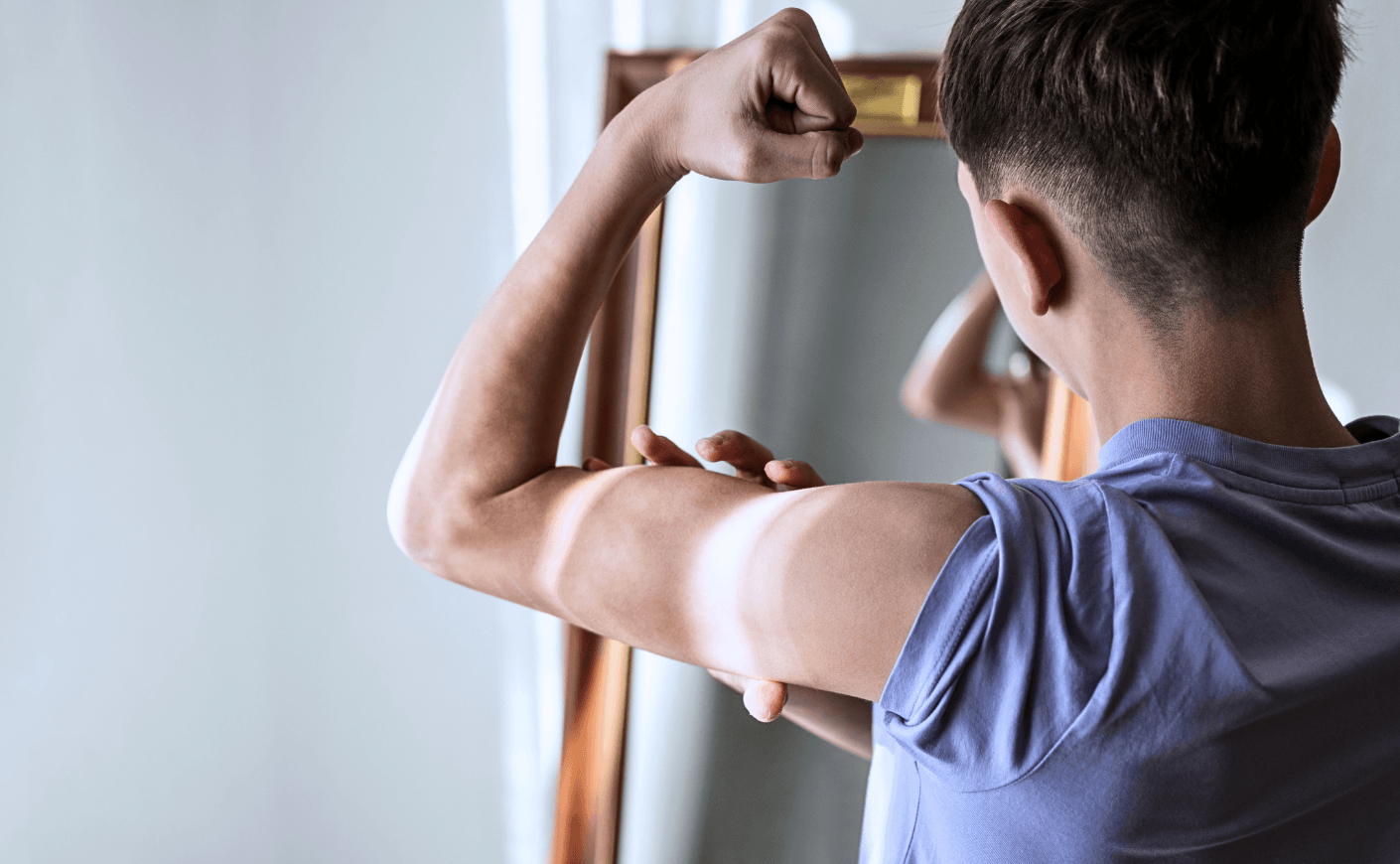 teenage boy flexing in mirror