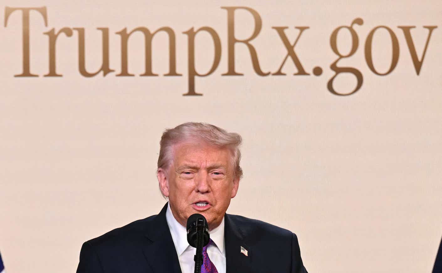 trump in front of a TrumpRX sign
