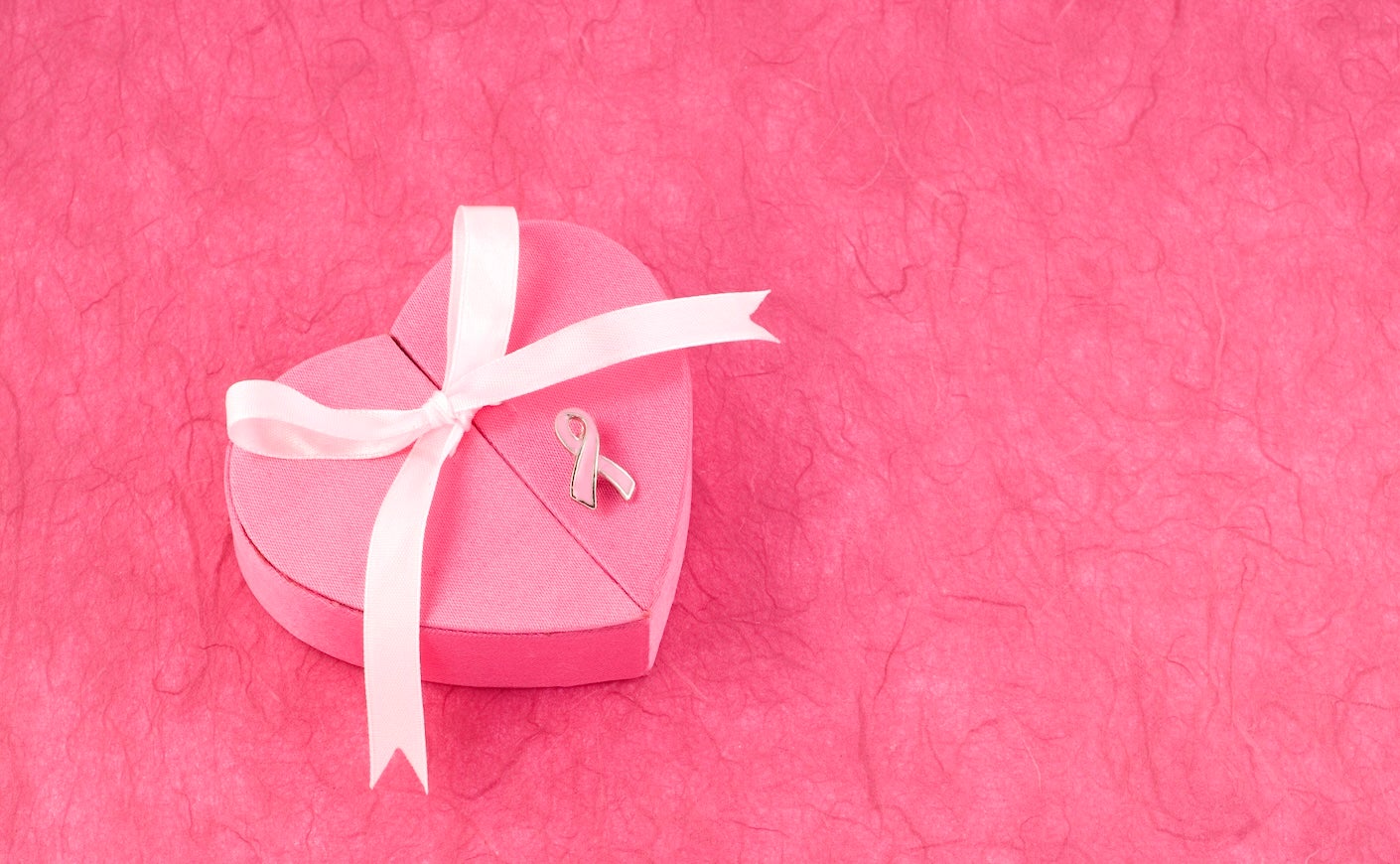 Pink heart-shaped box with pink breast cancer ribbon pinned to it