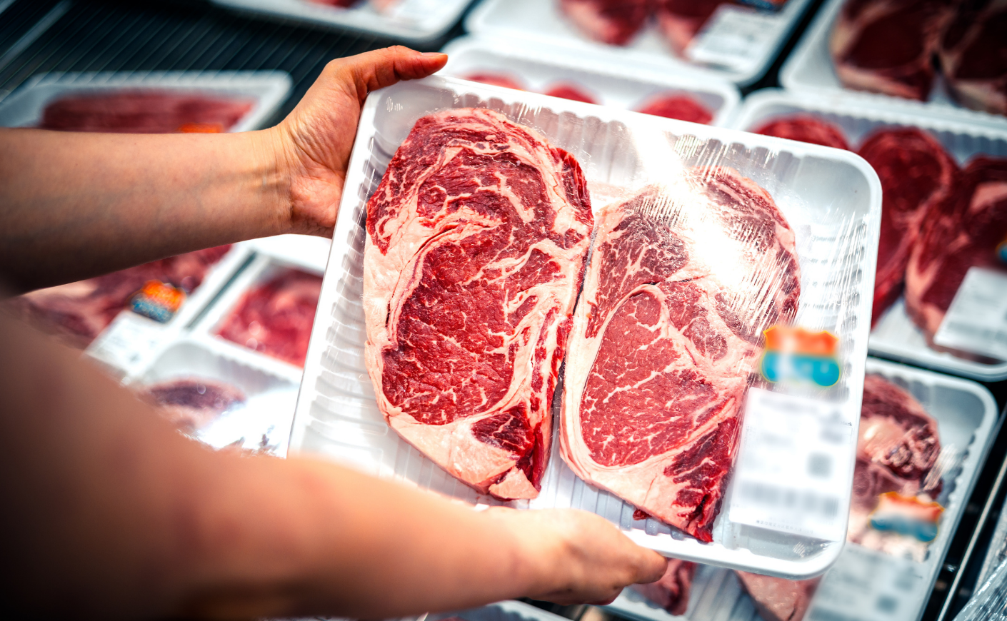 woman checking price of beef at the supermarket