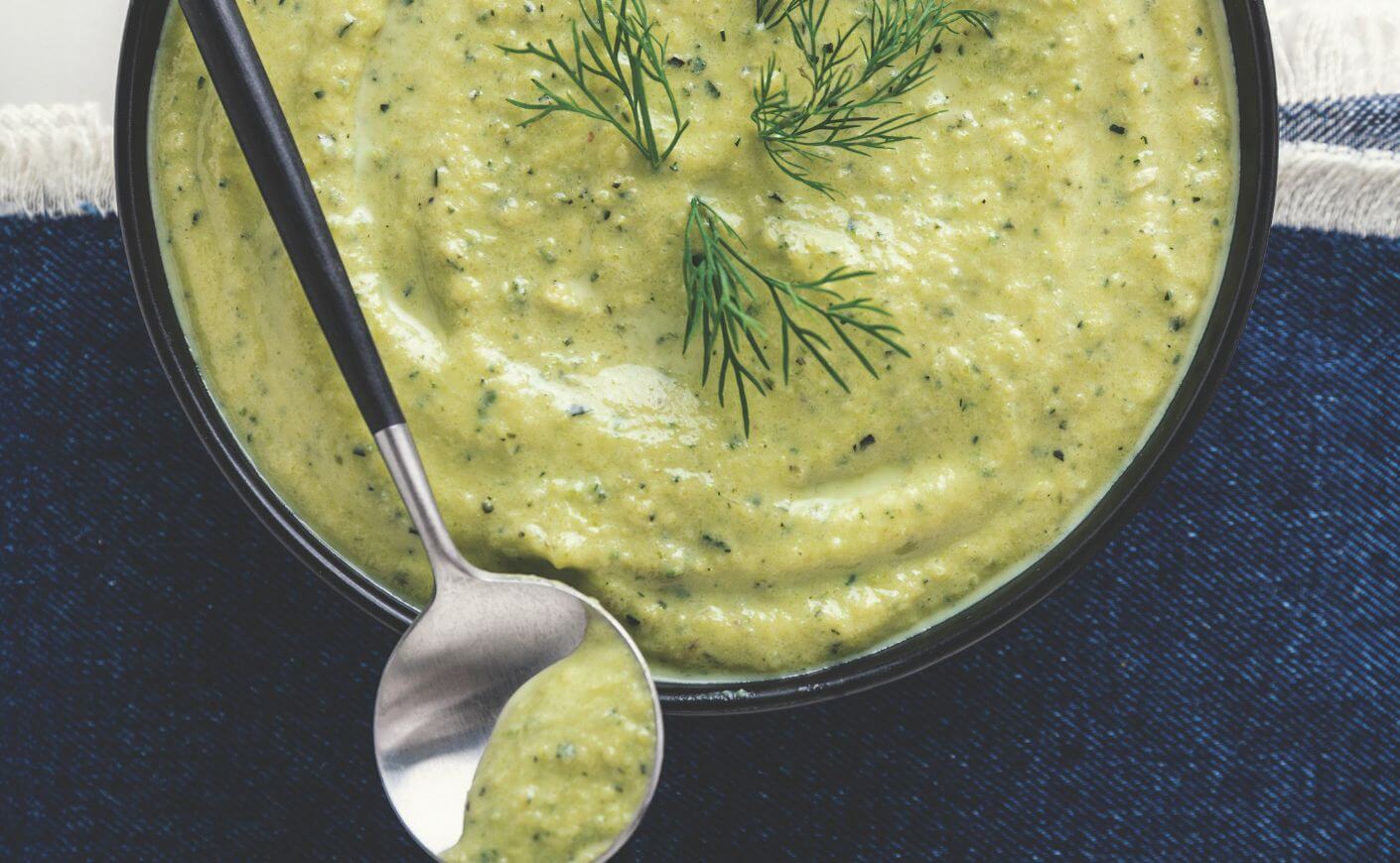A bowl and spoonful of zucchini dill bisque.