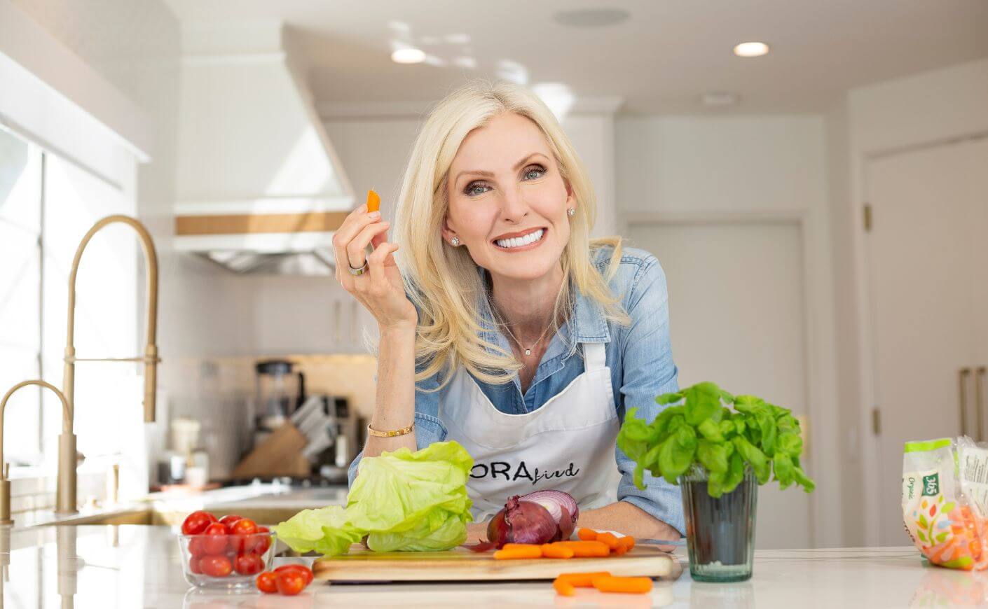 Lora McLaughlin Peterson leaning over her kitchen counter, surrounded by vegetables.