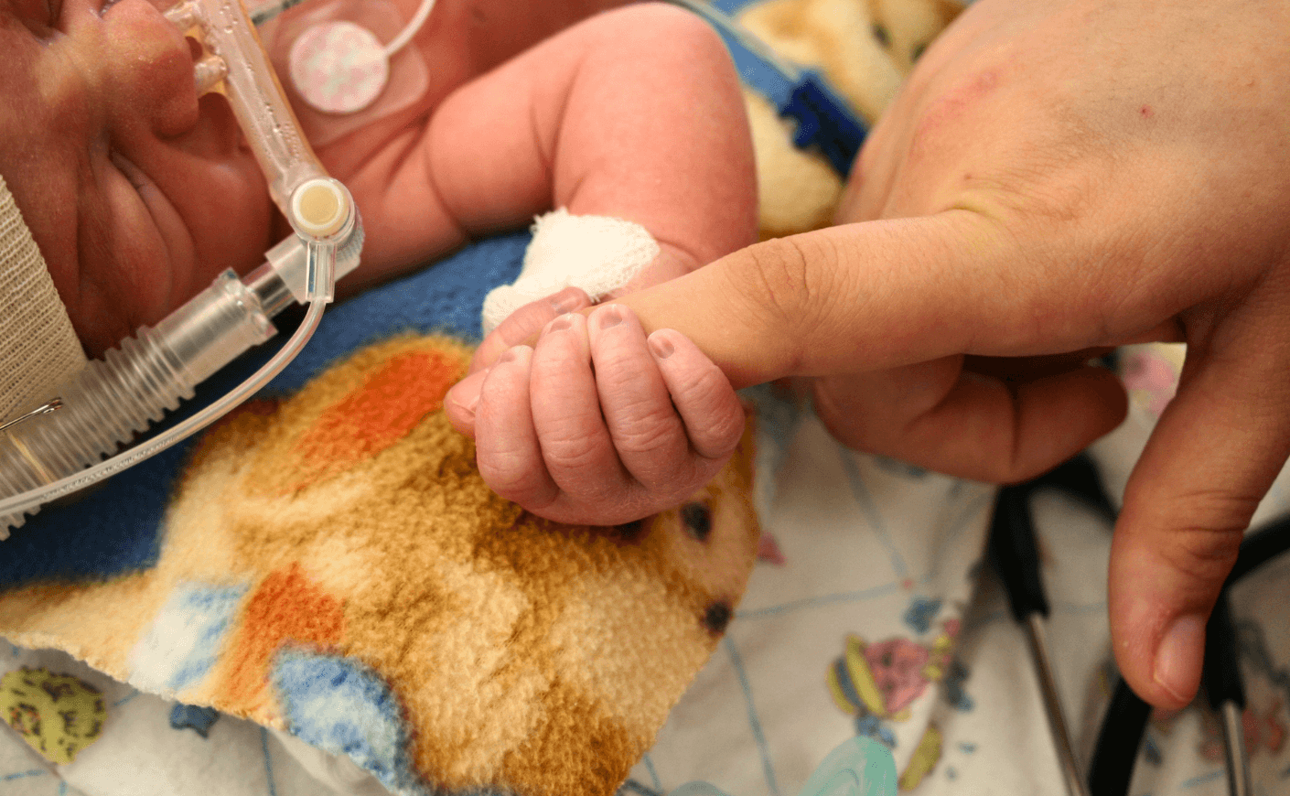 baby holding mother's hand in hospital
