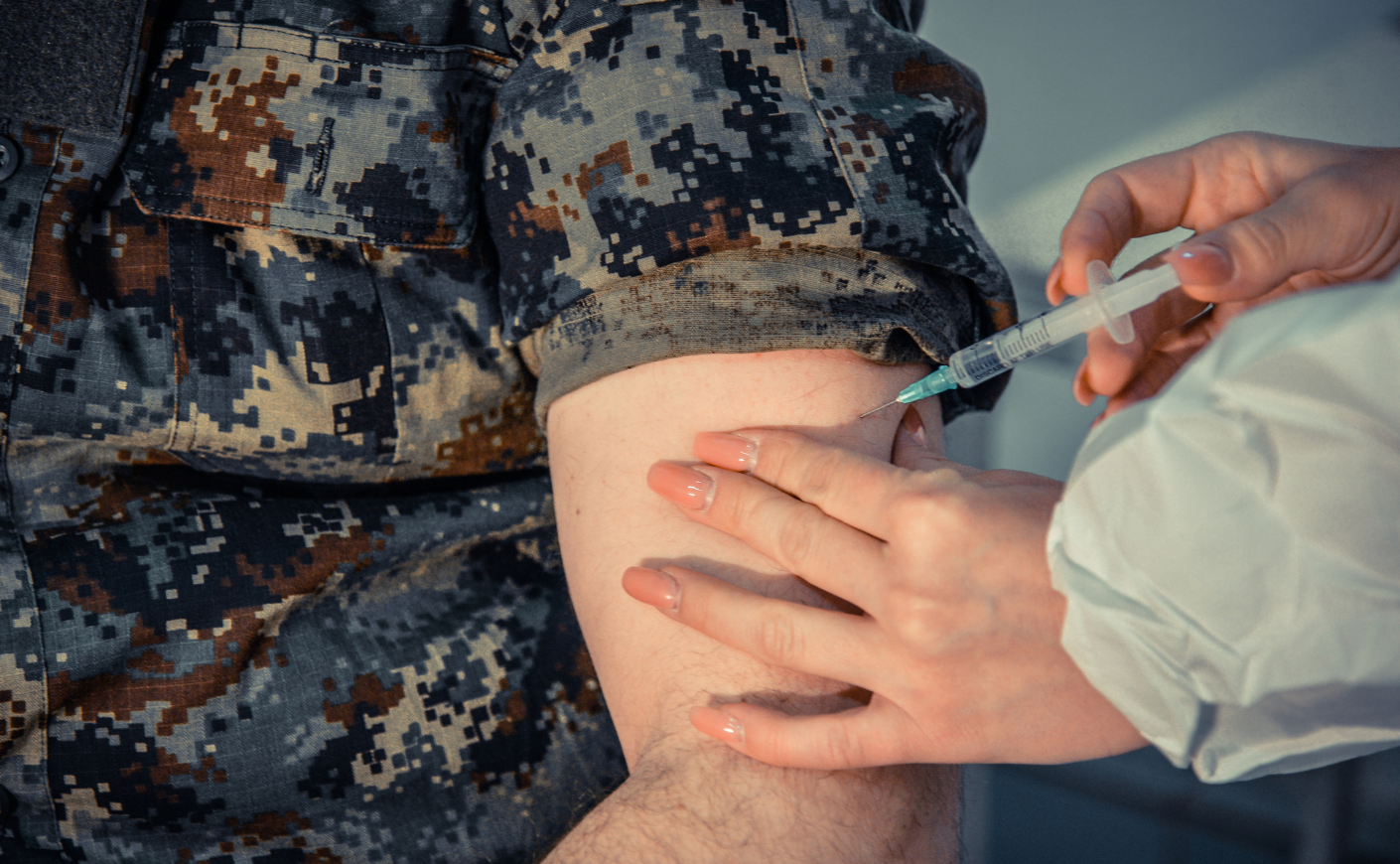 Person in military garb being given a shot