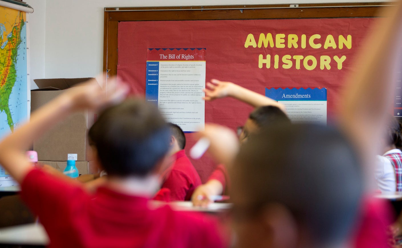 students raising their hand in a history class