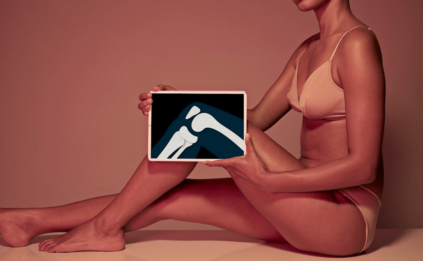 Young woman holding tablet in front of leg to display knee bone