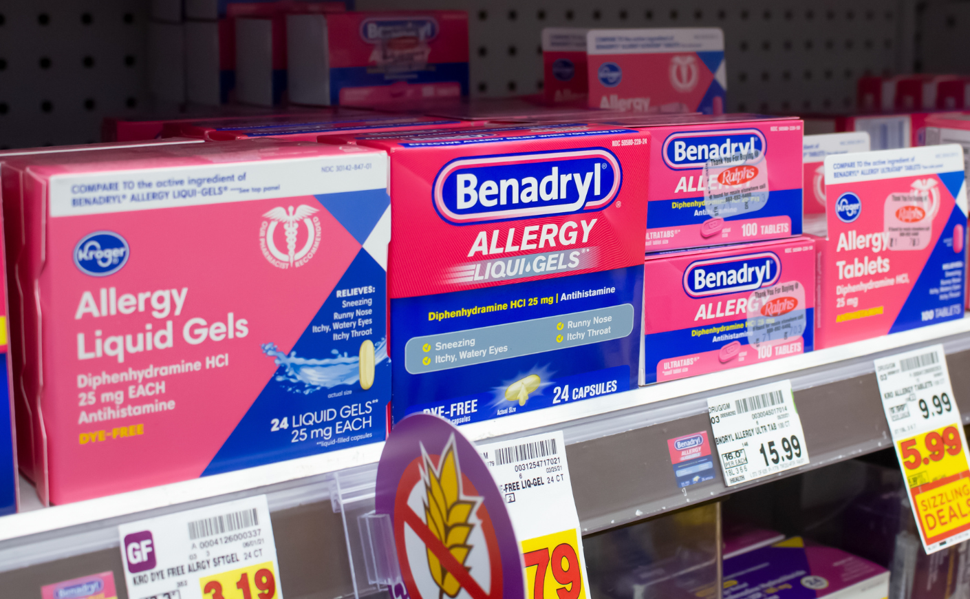 Pink boxes of benadryl on a pharmacy shelf