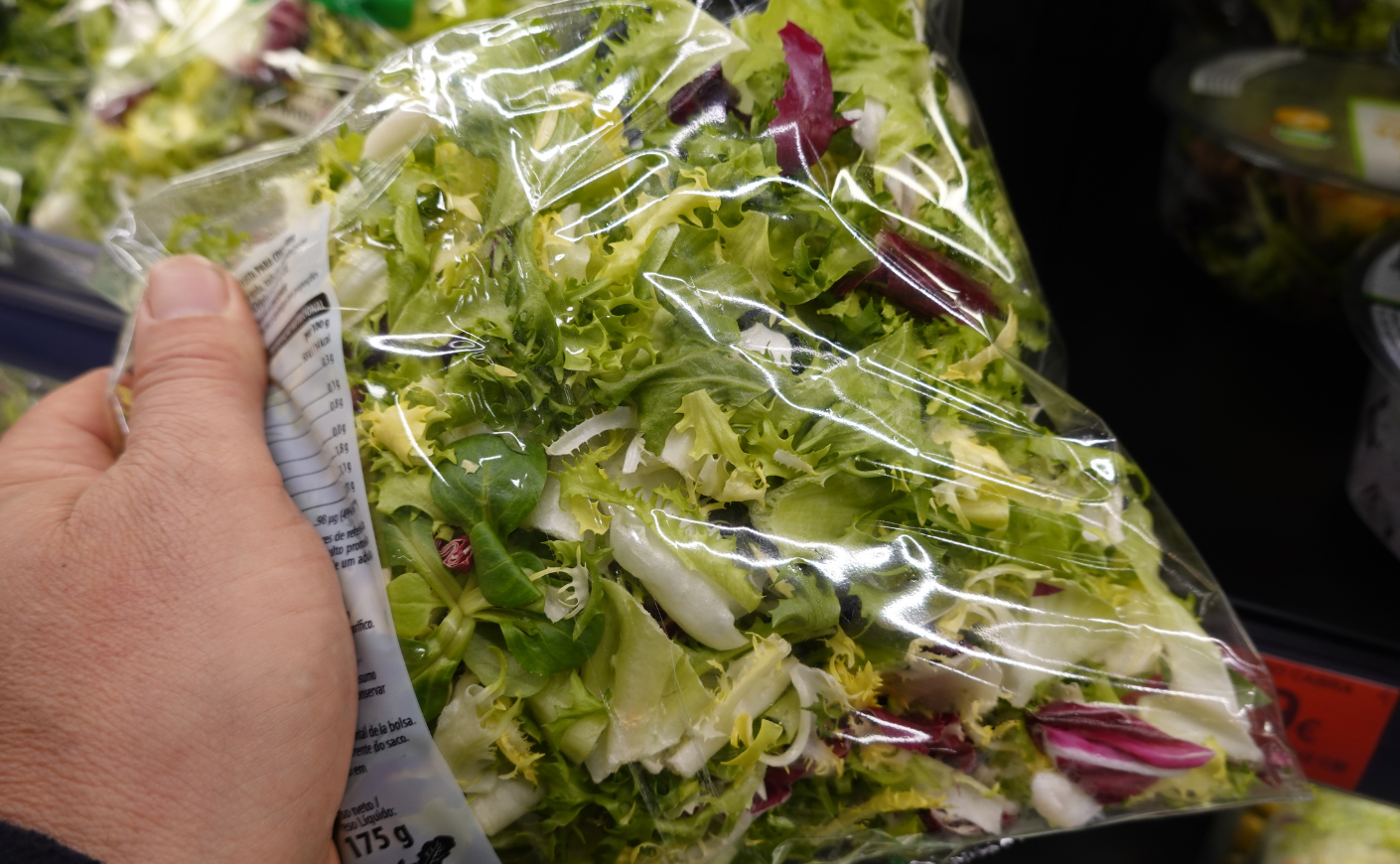 person holds bag of lettuce