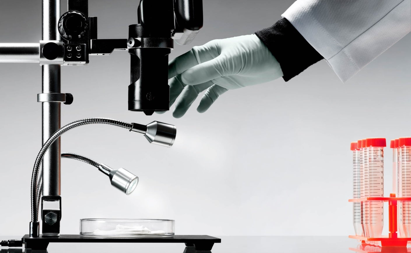 Hand touching a microscope