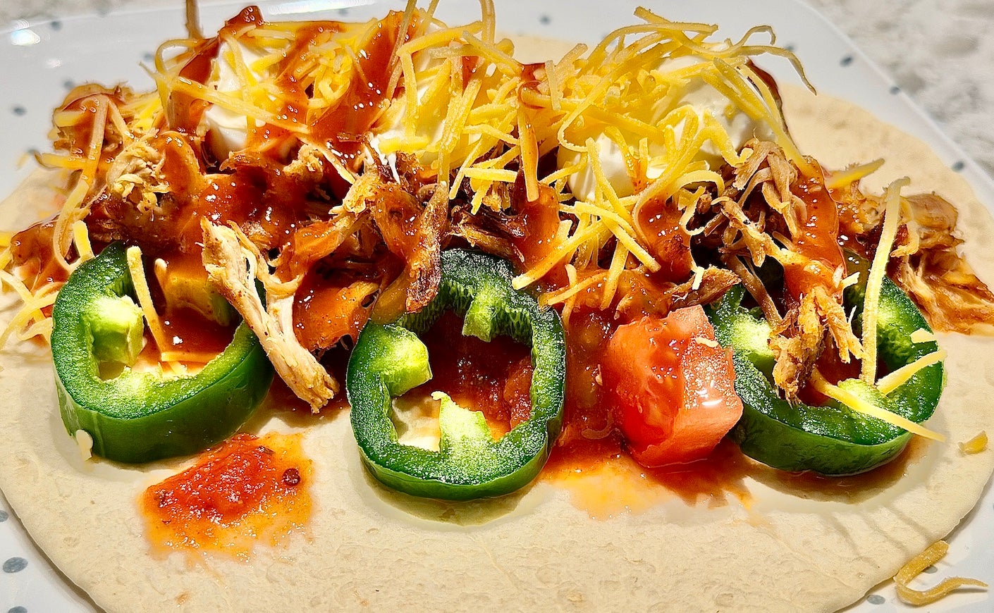 Loaded soft carnitas taco with cheese, salsa, tomato, jalapeño, sour cream and taco sauce.