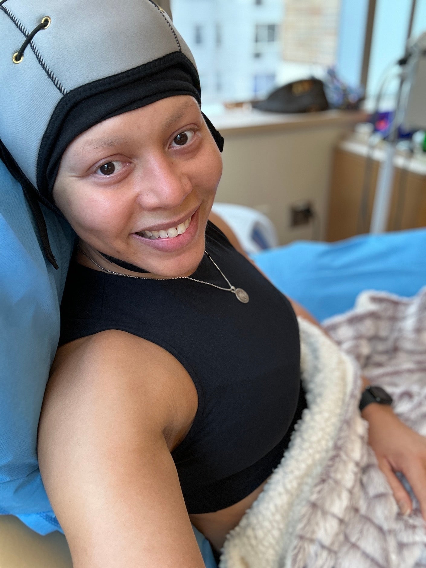 woman wearing a scalp cooling hat smiling at the camera