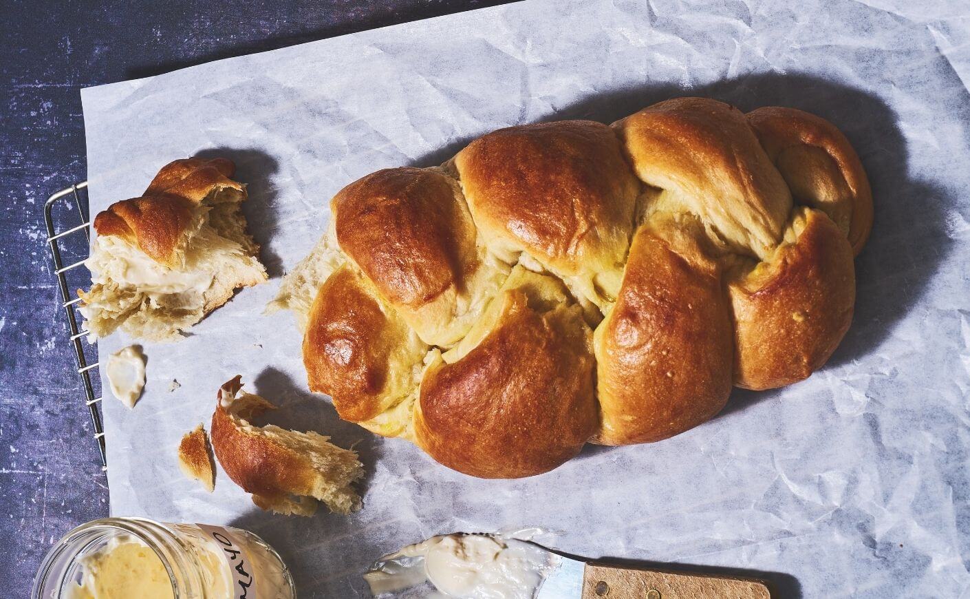 A loaf of challah alongside a ramekin of mayonnaise.