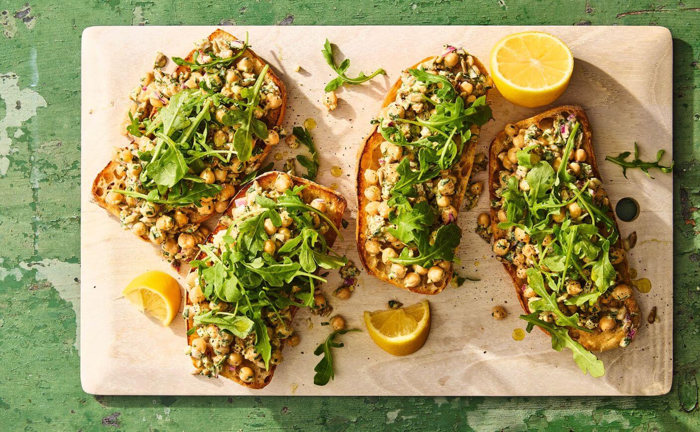 A tray of open-faced green goddess chickpea salad sandwiches.