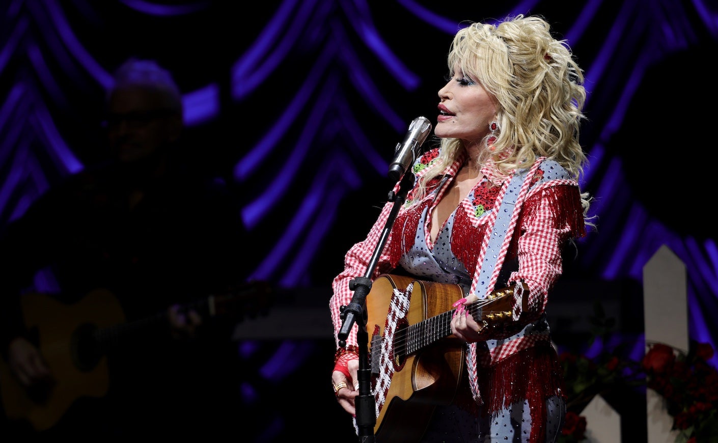 dolly parton on stage holding a guitar and singing