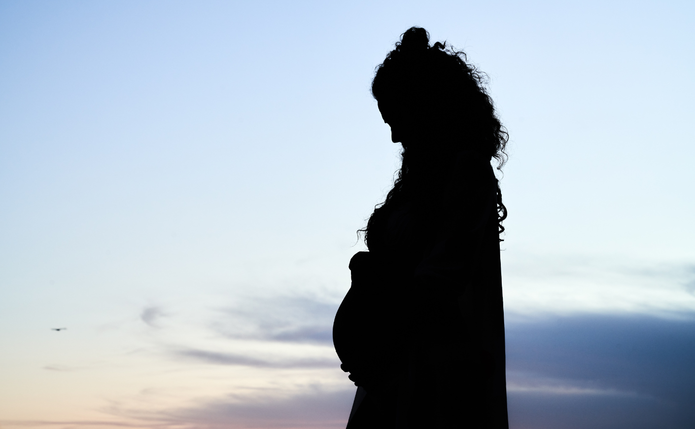 pregnant woman silhouetted against blue sky