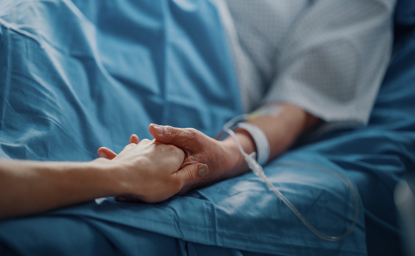 Senior Woman Resting in a bed with Finger Heart Rate Monitor, Caring Family Member Holds Her Fragile Hand,