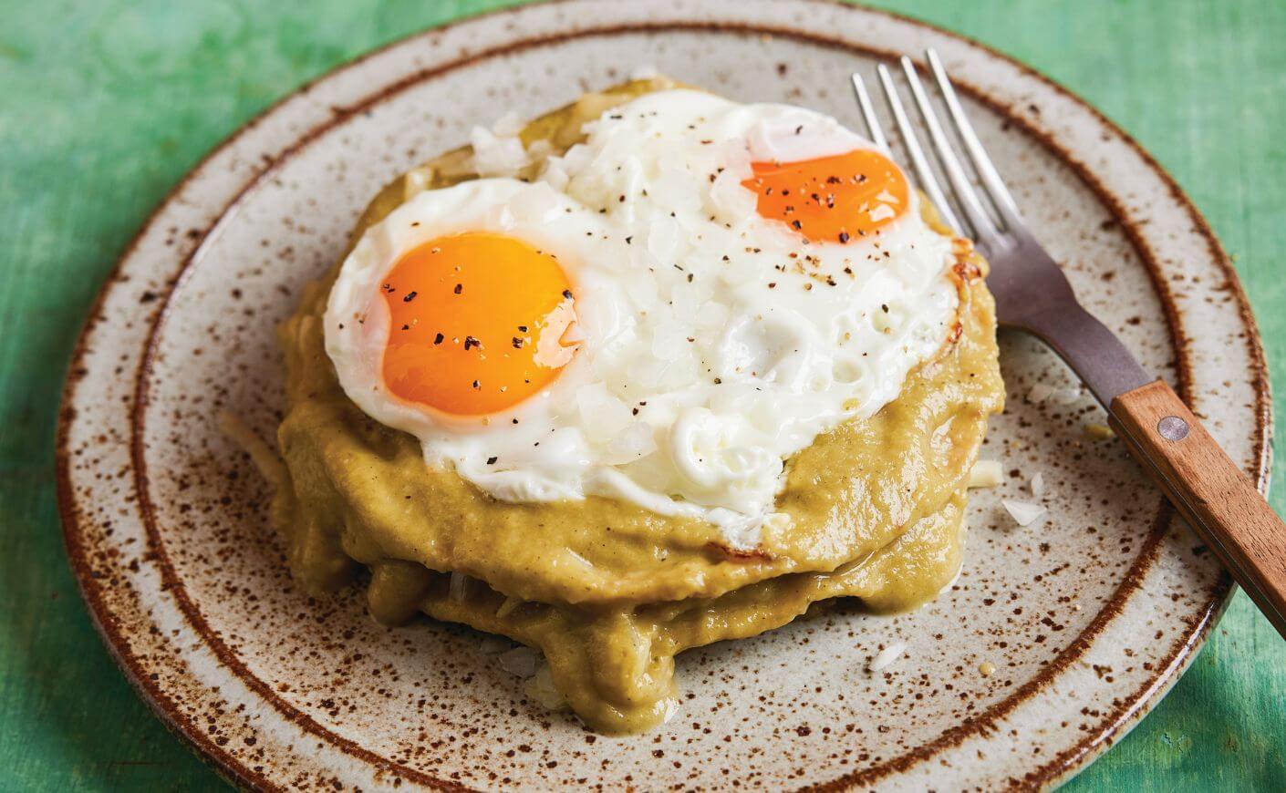 A plate of stacked enchiladas and eggs.