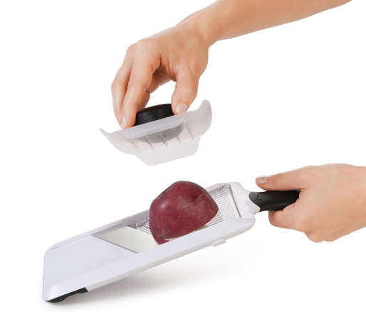 Hands slicing an onion with a mandoline.