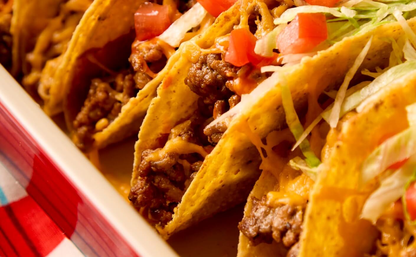 A baking dish full of tacos.