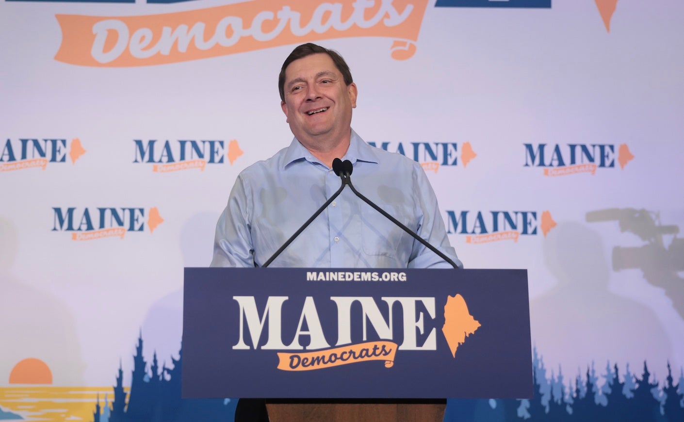 troy jackson speaking in front of a Maine Democrats sign.