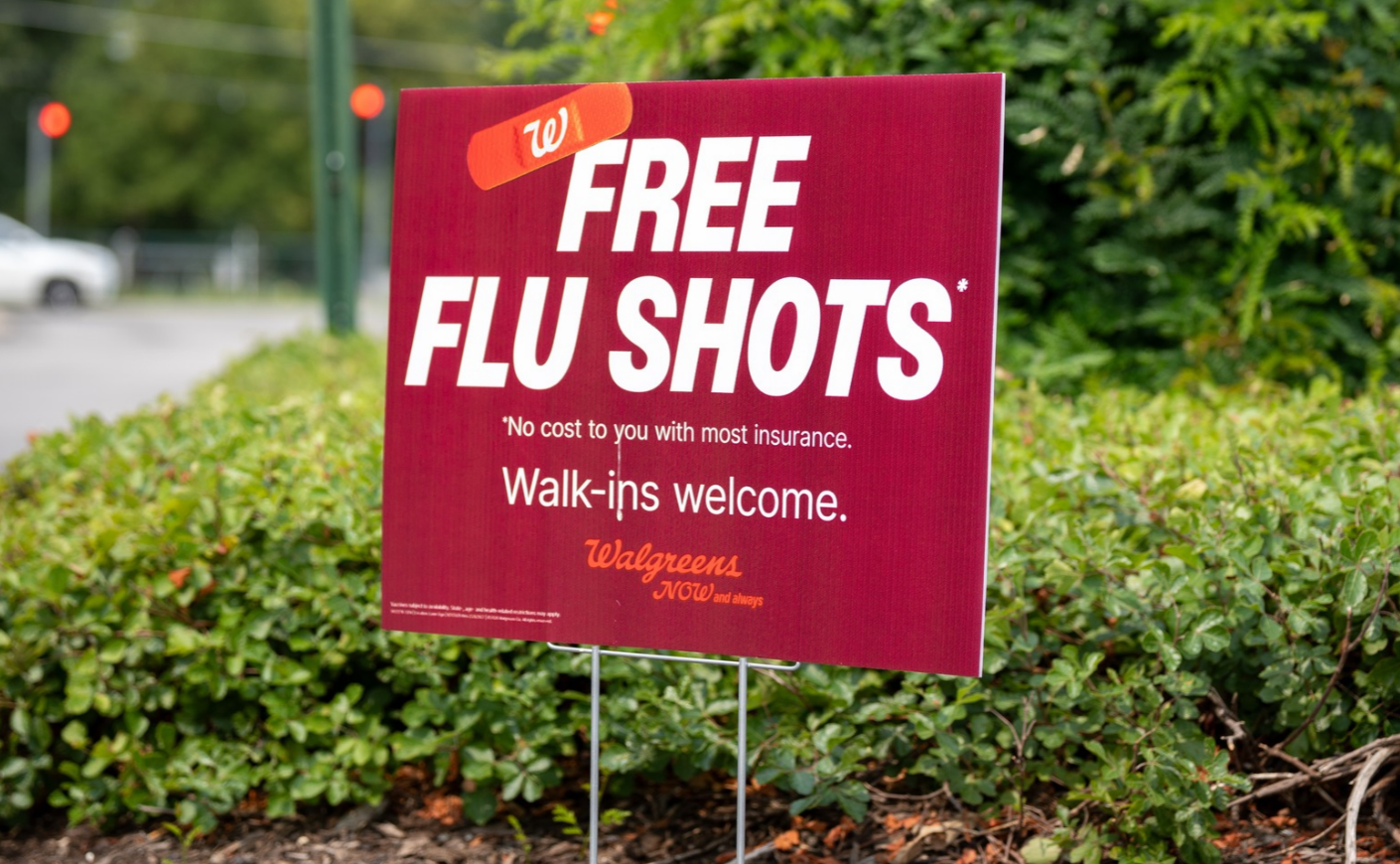 Red Walgreens sign advertising: Free Flu shots *no cost to you with most insurance. Walk-ins welcome.