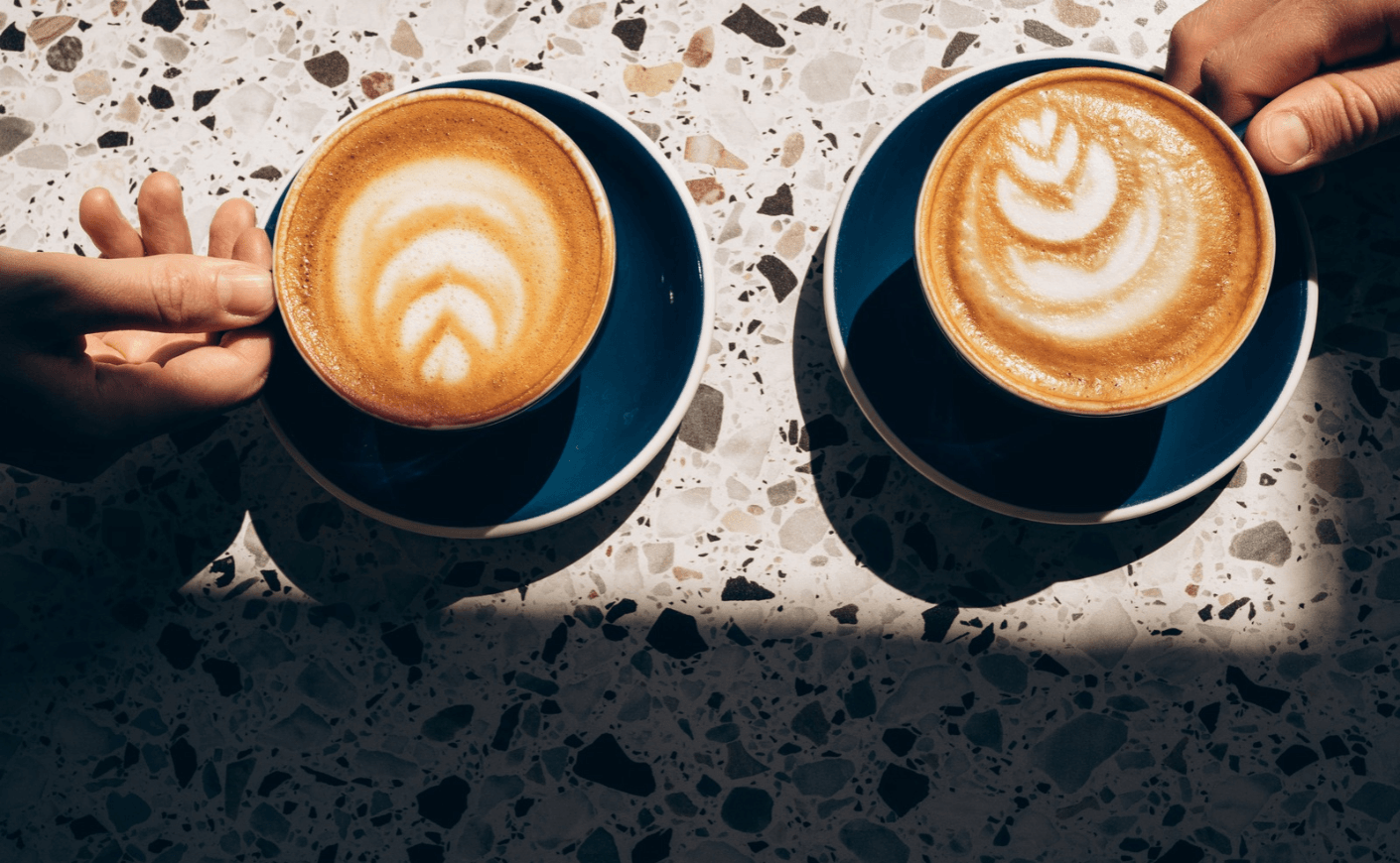 two hands with coffee cups