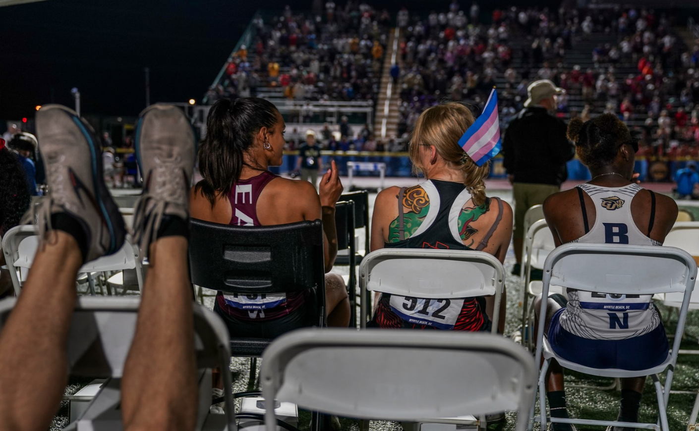 Sadie Schreiner, who finished 3rd in the 200m race, wears a transgender flag in her hair while chatting with first place finisher, Lauren Jarrett before they head to the awards stand after Sadie finished 3rd in the finals of the 200m race at the 2024 NCAA DIII outdoor track and field championships at Doug Shaw Memorial Stadium on May 25, 2024, in Myrtle Beach, SC.